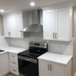 Image of a renovated kitchen having black cook stove and white cupboards